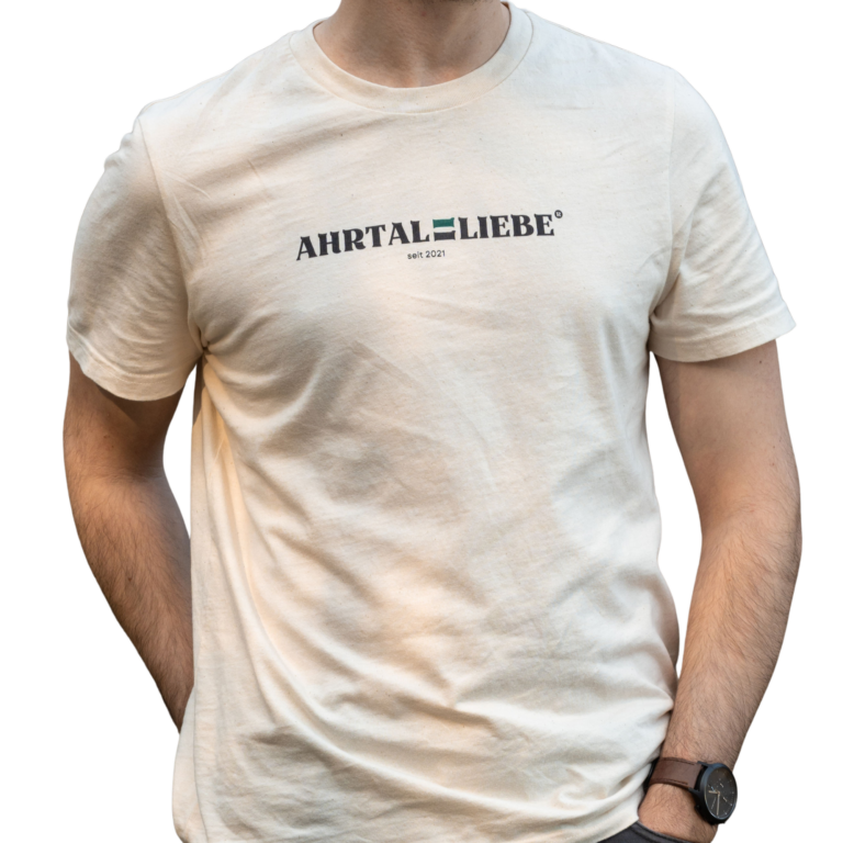 Beiges Herren-T-Shirt mit schwarzem Aufdruck „AHRTALLIEBE seit 2021“. Die Person trägt das Shirt locker mit einer Hand in der Hosentasche, das Design wirkt schlicht, modern und regional inspiriert.